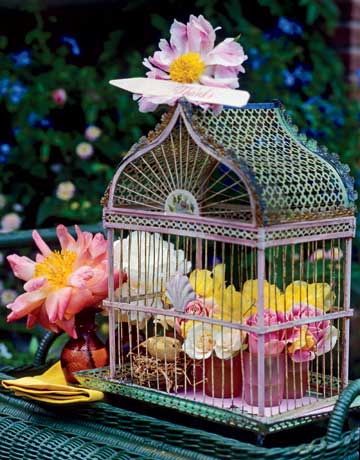 The image features a lovely iron birdcage with little pink glasses and roses